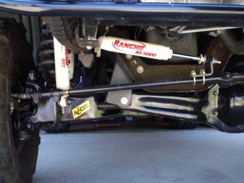 1996 Ford Bronco - Lifted front suspension underside with white Rancho RS5000 and RSX shocks and an ACCEL steering stabilizer.