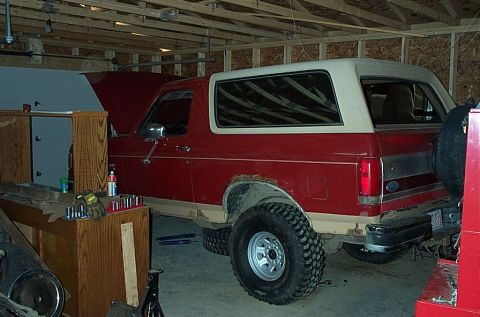 1987 Ford Bronco - A red and white 1987 Ford Bronco is shown in a garage with its hood up and lifted suspension.
