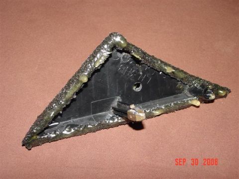1993 Ford Probe - A modified plastic part, possibly from a vehicle, shows extensive sealant application around its edges.