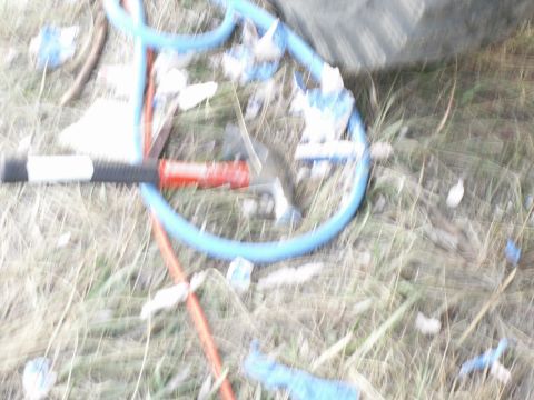 1977 Ford F-250 - Jump starter cables and a hammer are on the ground amidst grass and debris.