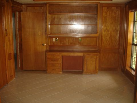 1989 Ford Bronco - Interior room with wood paneling, built-in desk, and shelves. Tiled floor visible.