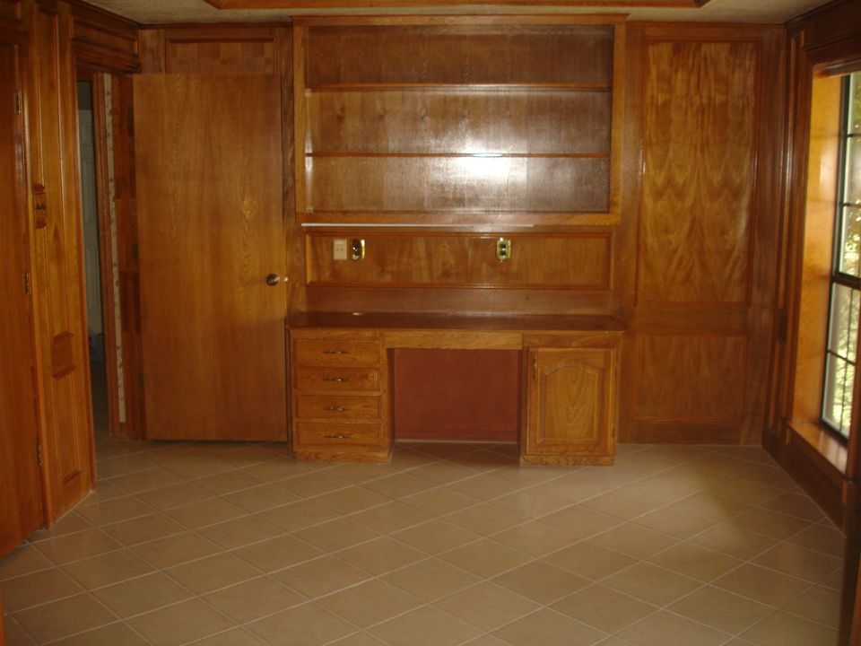 Interior room with wood paneling, built-in desk, and shelves. Tiled floor visible