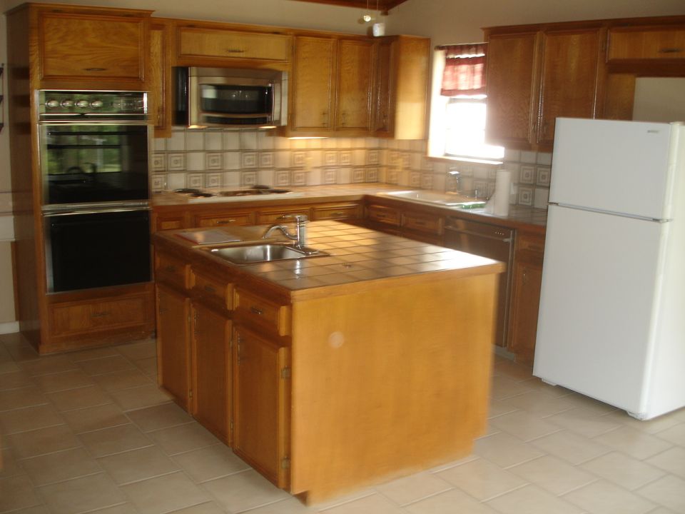 Kitchen with wood cabinets, island sink, and white refrigerator