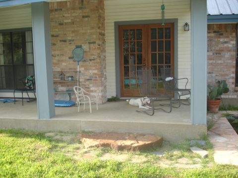 1989 Ford Bronco - A white dog rests on a concrete porch in front of a house with double doors and brick accents.