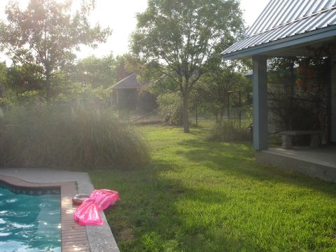 1989 Ford Bronco - A sunny day in the backyard shows a pool, lawn, and a house with a covered porch.