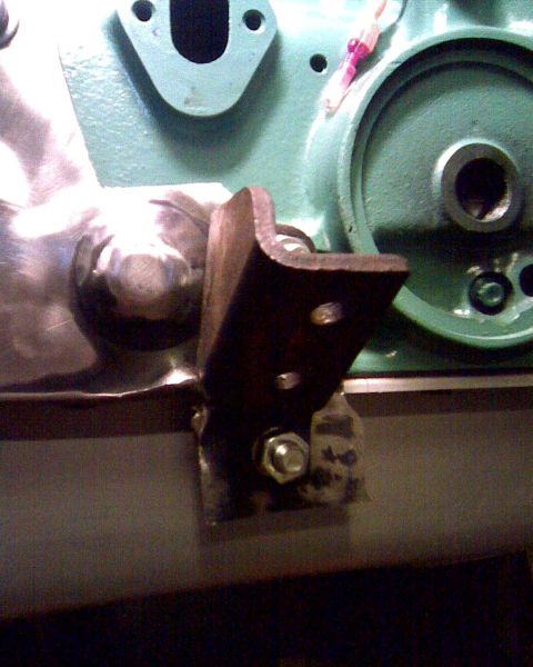 1953 Ford Mainline - Close-up of a metal bracket attached to a green engine component, with visible bolts and a circular flange.