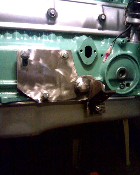 1953 Ford Mainline - Close-up of an engine block with a custom metal plate and bracket attached, revealing mechanical components.