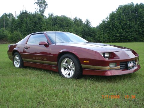 1979 Chevrolet Camaro - Maroon Chevrolet Camaro IROC-Z with gold trim, parked outdoors on a grassy lawn.