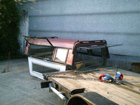 2001 Dodge 2500 - Two truck bed caps are secured with chains to a flatbed trailer, ready for transport.