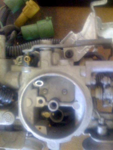 1994 Ford Bronco - A close-up view of a carburetor, green and yellow electrical connectors and visible internal components.