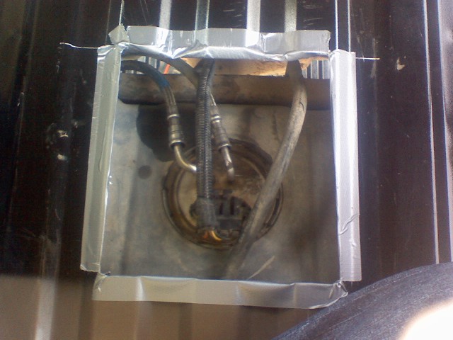 Fuel pump assembly with hoses, secured with tape and wood