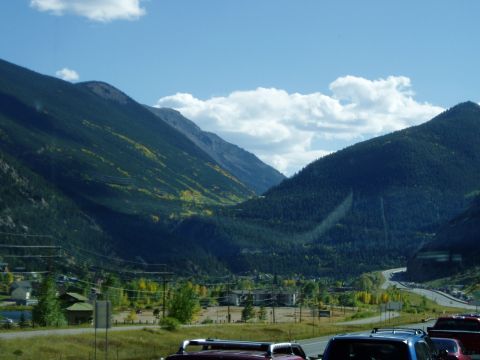 1995 Mercury Grand Marquis - A scenic mountain valley with a winding highway and scattered buildings under a blue sky with clouds.