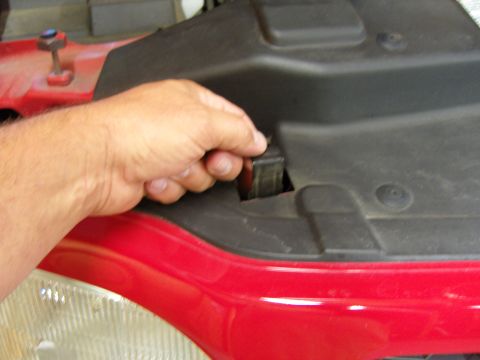 2007 Ford Mustang - A hand is shown operating a latch on a red vehicle's engine bay.