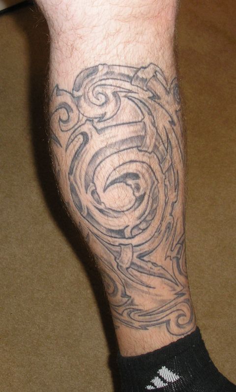 1995 Ford Bronco - A black ink tribal tattoo covers the lower leg, swirling patterns and sharp edges.