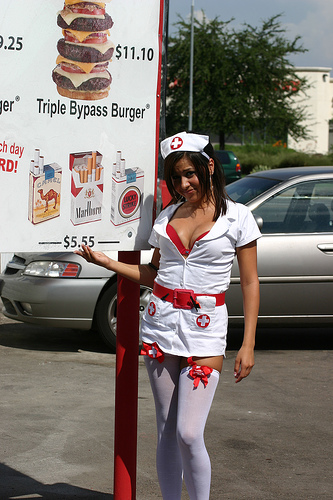 1989 Ford Bronco - A woman in a nurse costume poses next to a menu board, with a car visible in the background.
