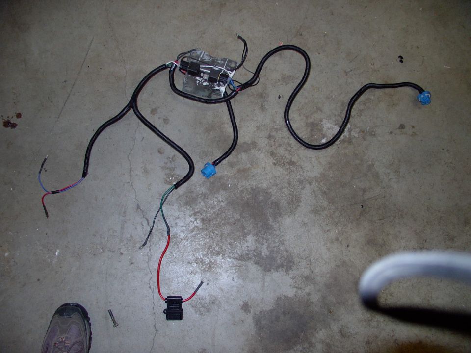 Far left note the two weatherpack type males to stick in the stock headlight socket for signal. Nearest the foot is the 40 amp Maxi fuse holder and common ground terminal. On the headlight support are the two relays with their pigtails and ground terminals.