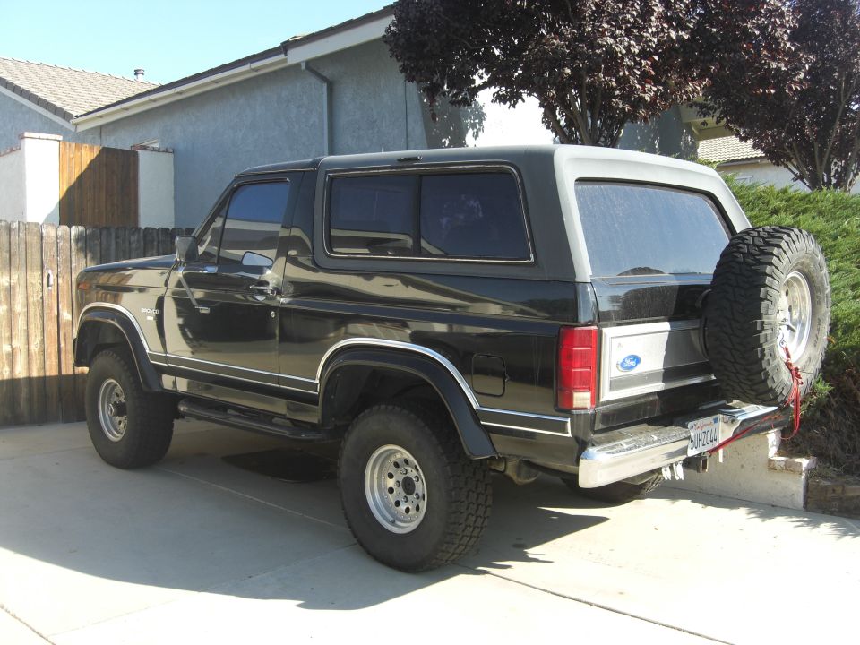 Black Ford Bronco with spare tire on back, parked in driveway