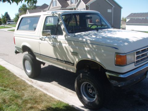 1987 Ford Bronco - This 1987 Ford Bronco is parked curbside on a sunny day, showing its classic SUV profile.