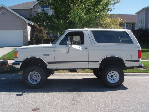 1987 Ford Bronco - This lifted 1987 Ford Bronco is parked on a street in front of a house.