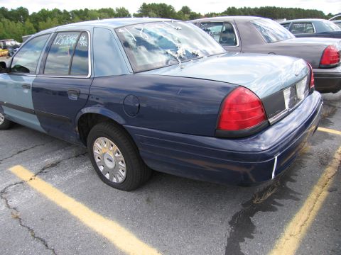 1991 Ford LTD Crown Victoria - A two-tone blue 1991 Ford Crown Victoria LTD is parked in a lot, showing a dented rear window and a flat tire.