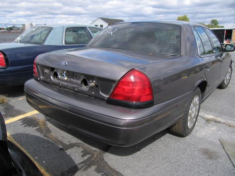 1991 Ford LTD Crown Victoria - A dark gray Ford Crown Victoria is parked next to another vehicle, showing its rear end.