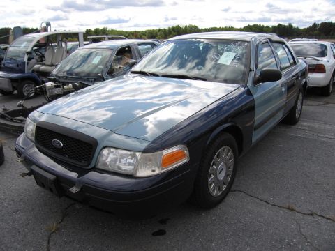1991 Ford LTD Crown Victoria - A two-tone Ford Crown Victoria is parked in a lot with other vehicles, showing its front and side profile.