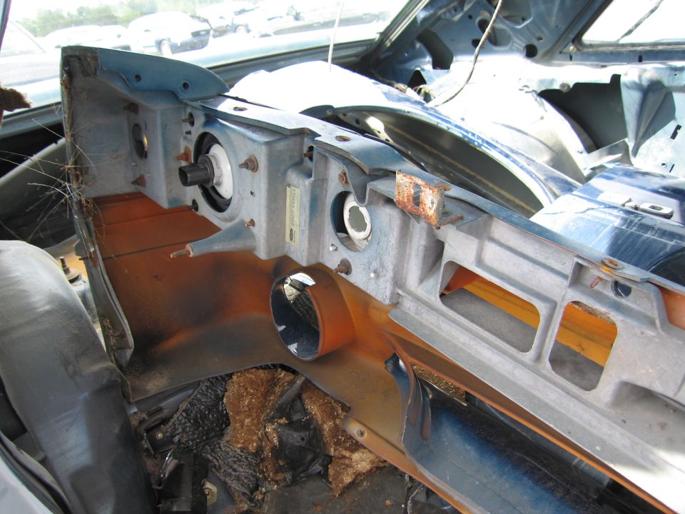 Interior dashboard of a dismantled vehicle, showing exposed metal and wiring