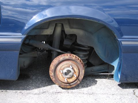 1991 Ford LTD Crown Victoria - Close-up of a car's rear suspension and brake drum assembly, with the drum removed.