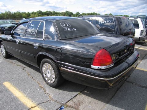 1991 Ford LTD Crown Victoria - A black sedan is parked in a lot with other vehicles. Numbers are written on the rear window.