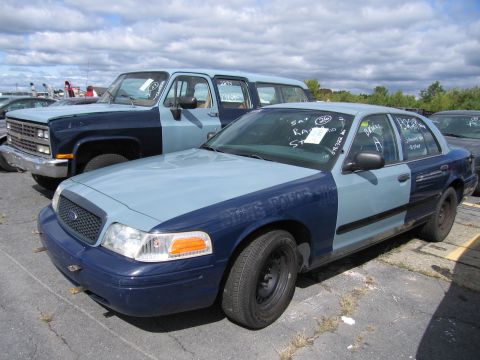 1991 Ford LTD Crown Victoria - Two-tone police car and SUV parked outdoors under a cloudy sky.