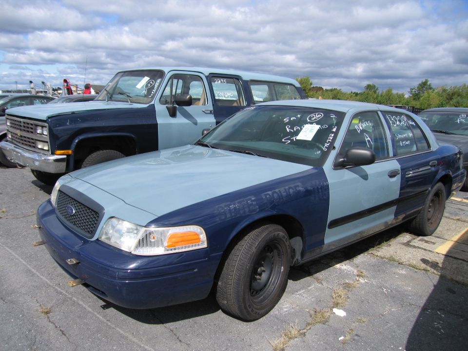 Two-tone police car, light blue and dark blue, parked next to a blue and dark blue SUV