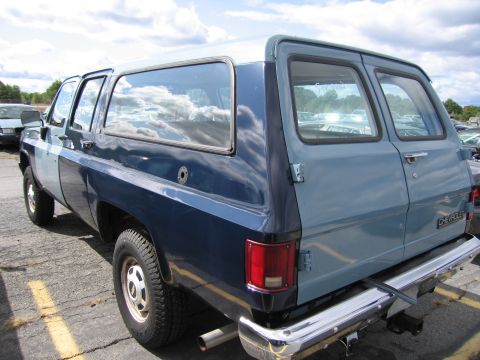 1991 Ford LTD Crown Victoria - The rear of a Chevrolet Suburban shows a chrome bumper and dual exhaust pipes.