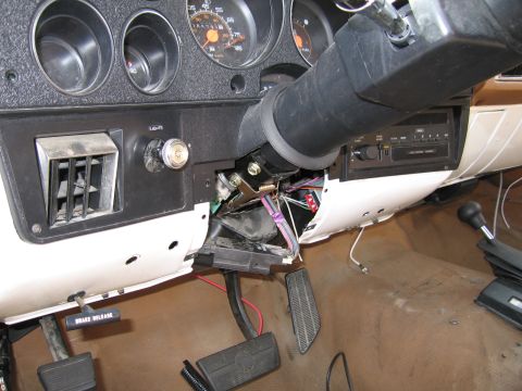 1991 Ford LTD Crown Victoria - The interior of a vehicle shows exposed wiring beneath the steering column and dashboard, with pedals visible on the floor.
