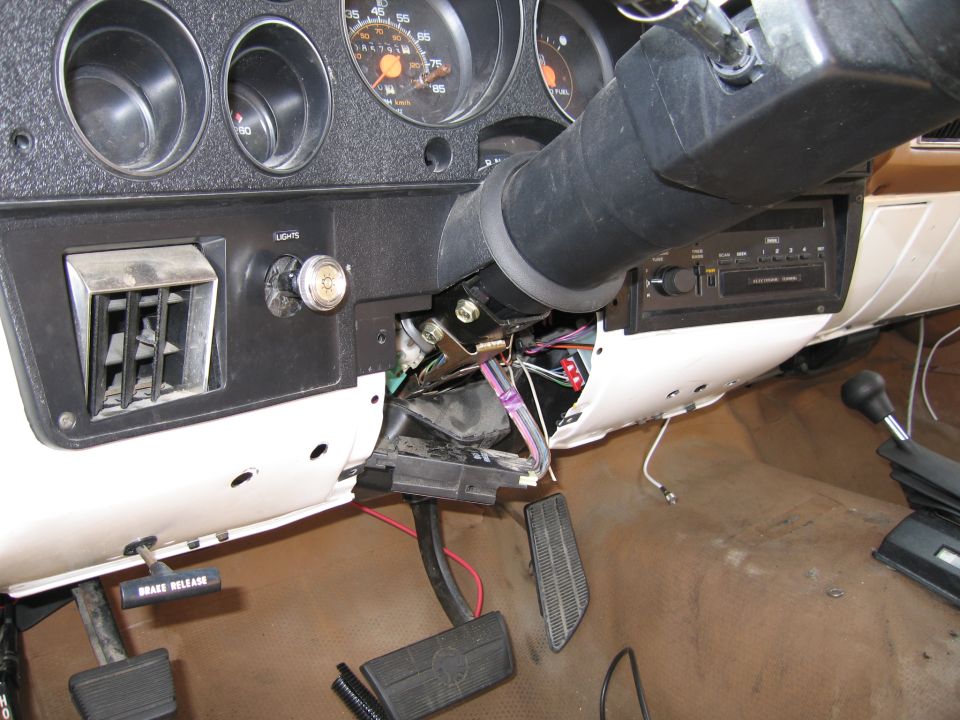 Interior view of a vehicle's dashboard with exposed wiring and pedals
