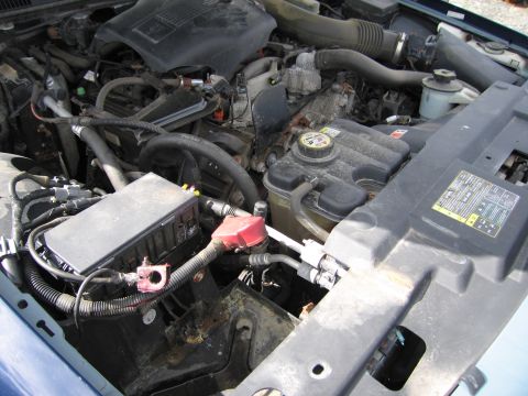 1991 Ford LTD Crown Victoria - Close-up view of a vehicle's engine compartment, showing the battery, fuse box, and cooling system components.