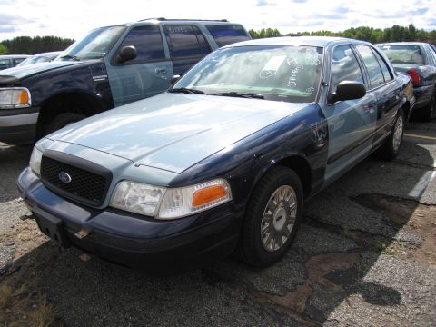 1991 Ford LTD Crown Victoria - A two-tone Ford Crown Victoria is parked next to an SUV. The car has a light blue hood and fenders with a dark blue body.