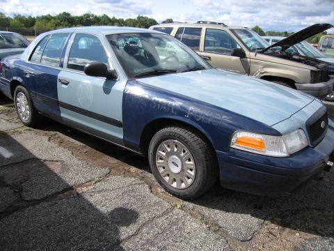 1991 Ford LTD Crown Victoria - A two-tone blue Ford Crown Victoria is parked next to a tan SUV with its hood open.
