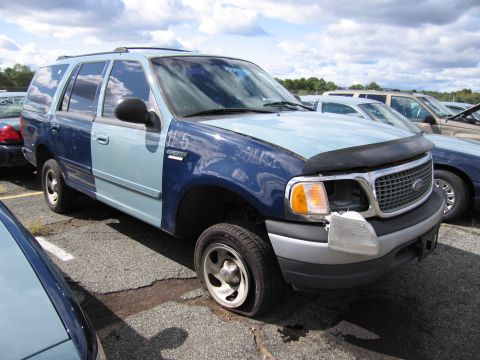 1991 Ford LTD Crown Victoria - This two-tone blue SUV, marked "115 EXPEDITION", has a flat tire and a missing headlight, with other vehicles visible in the background.