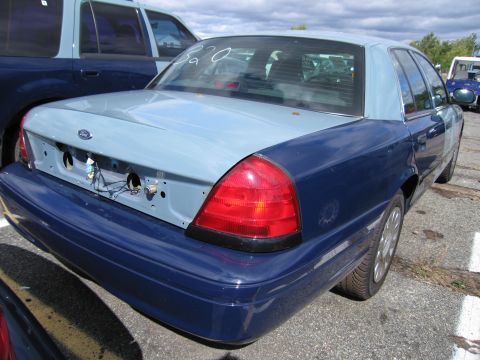 1991 Ford LTD Crown Victoria - The rear of a two-tone Ford Crown Victoria shows exposed wiring and mounting holes where a license plate would be.