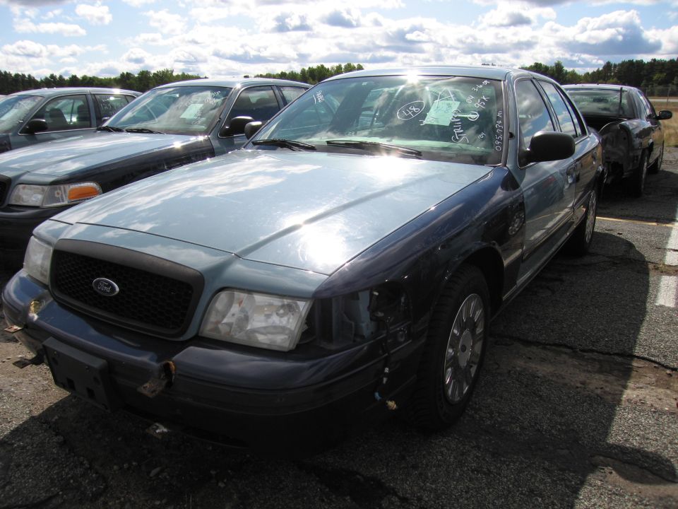 Light blue and dark blue 1991 Ford Crown Victoria LTD, front passenger side view. Multiple vehicles in background