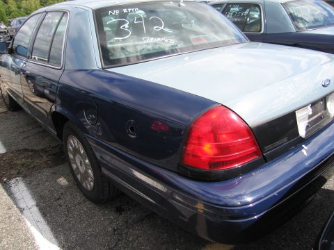 1991 Ford LTD Crown Victoria - A two-tone Ford Crown Victoria is parked in a lot with other vehicles, showing writing on its rear window.