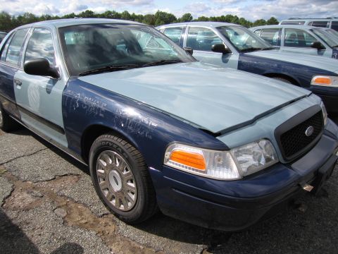 1991 Ford LTD Crown Victoria - A two-tone Ford Crown Victoria is parked in a lot with other similar vehicles visible in the background.