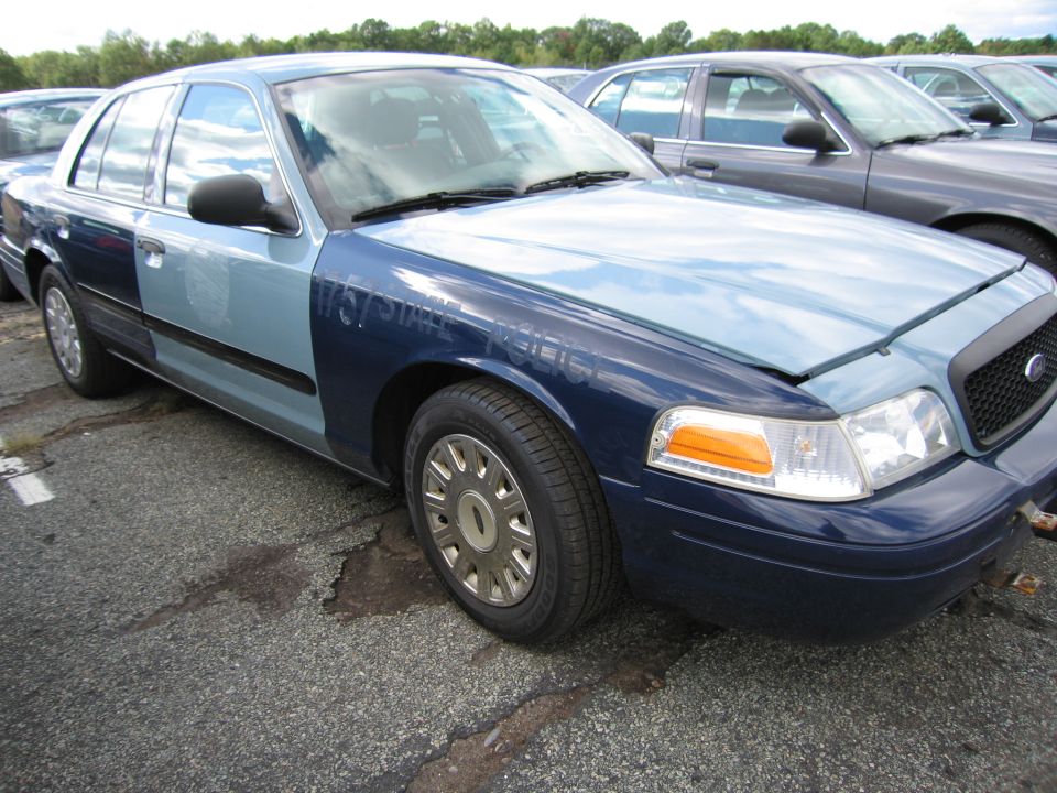 Two-tone Ford Crown Victoria, one side light blue, the other dark blue, with "STATE POLICE" text visible on the fender