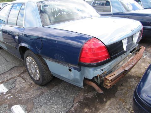 1991 Ford LTD Crown Victoria - A damaged Ford Crown Victoria is parked outdoors with visible text on its rear window.