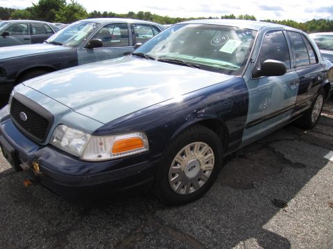 1991 Ford LTD Crown Victoria - This Ford Crown Victoria has a light blue hood and fenders, with a dark blue body. It is parked in a lot with other vehicles.