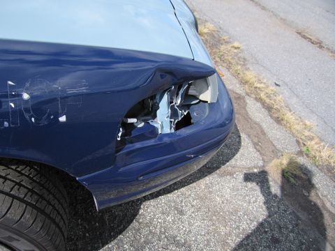 1991 Ford LTD Crown Victoria - The front passenger side of a car shows significant damage to the fender and headlight assembly.