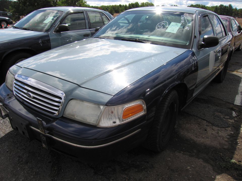 Front 3/4 view of a two-tone Ford Crown Victoria, one car behind another