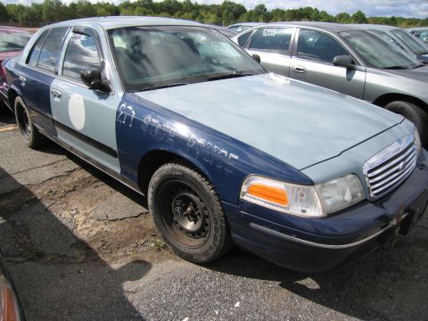 1991 Ford LTD Crown Victoria - This car has a two-tone paint job and some markings on the fender. It is parked in a lot with other vehicles.