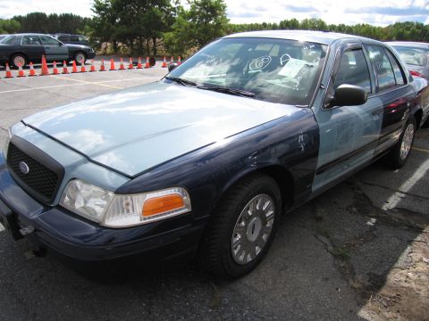1991 Ford LTD Crown Victoria - A two-tone blue sedan is parked in an outdoor lot with orange traffic cones in the background.
