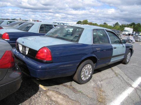 1991 Ford LTD Crown Victoria - Two Ford Crown Victorias are parked in a lot under a cloudy sky.
